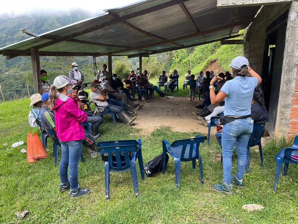 Image of a community gathering discussing coffee cultivation in Colombia, highlighting local farmers and collaboration.