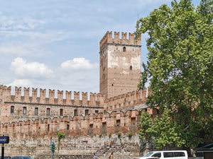 View of a historic brick tower surrounded by fortifications under a blue sky with fluffy clouds.