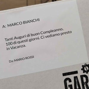 Messaggio di auguri stampato e adesivo su scatola con testo di auguri di compleanno da Mario Rossi a Marco Bianchi.